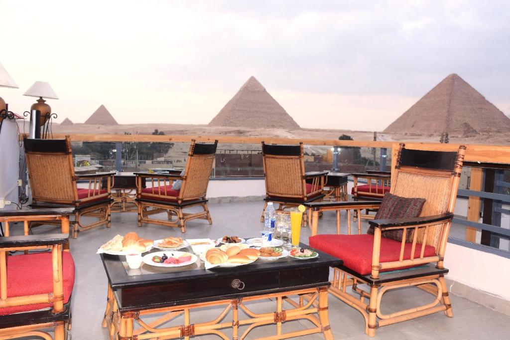 una mesa con comida en un balcón con vistas a las pirámides. en Pyramids Nun INN en El Cairo