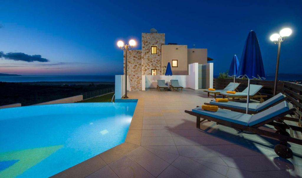a villa with a swimming pool at night at Iliada by Vintage Travel in Maleme