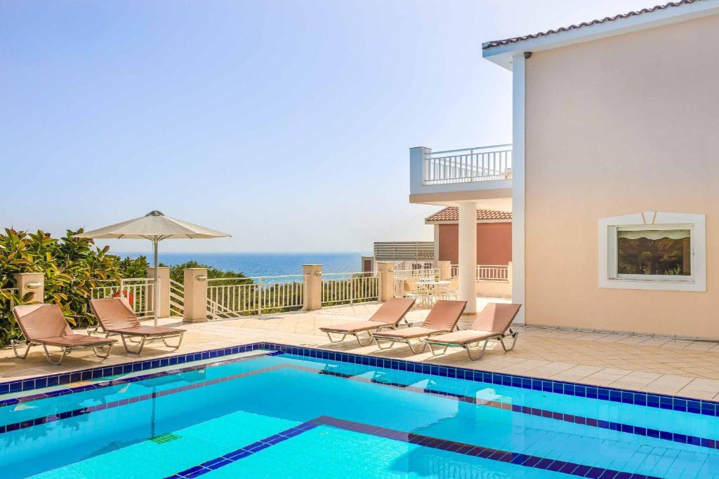 a swimming pool with chairs and a view of the ocean at Villa Angeliki Skala in Spathíon