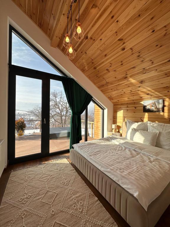 een slaapkamer met een groot bed en een groot raam bij Zenit Chalet Sohodol-Bran in Sohodol