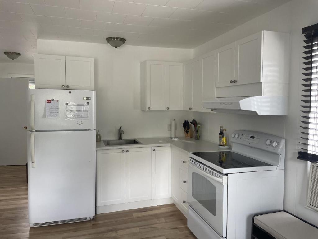 a white kitchen with white appliances and white cabinets at 4 Pièces, stationnement et tennis in Saguenay