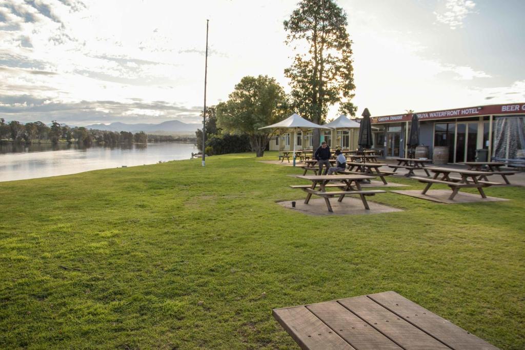 a picnic table on a grassy area next to a body of water at Moruya Waterfront Hotel Motel in Moruya