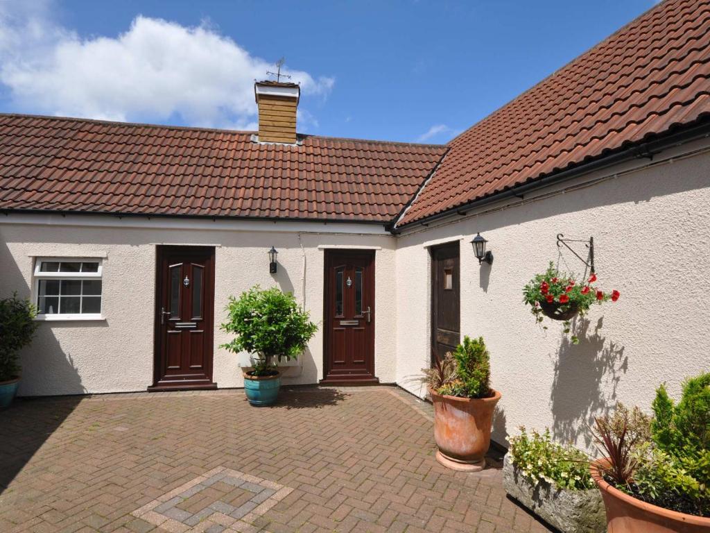 a white house with brown doors and potted plants at 1 bed in Burnham-on-Sea ALPAD in Highbridge