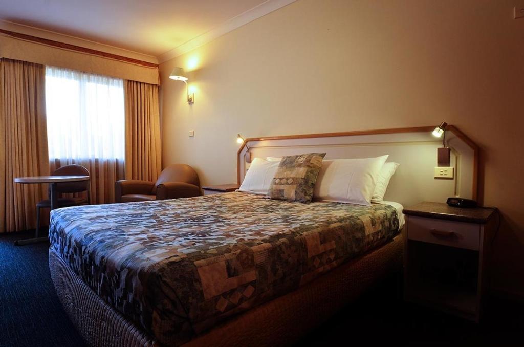 a hotel room with a bed and two lamps at The Crossing Motel in Junee