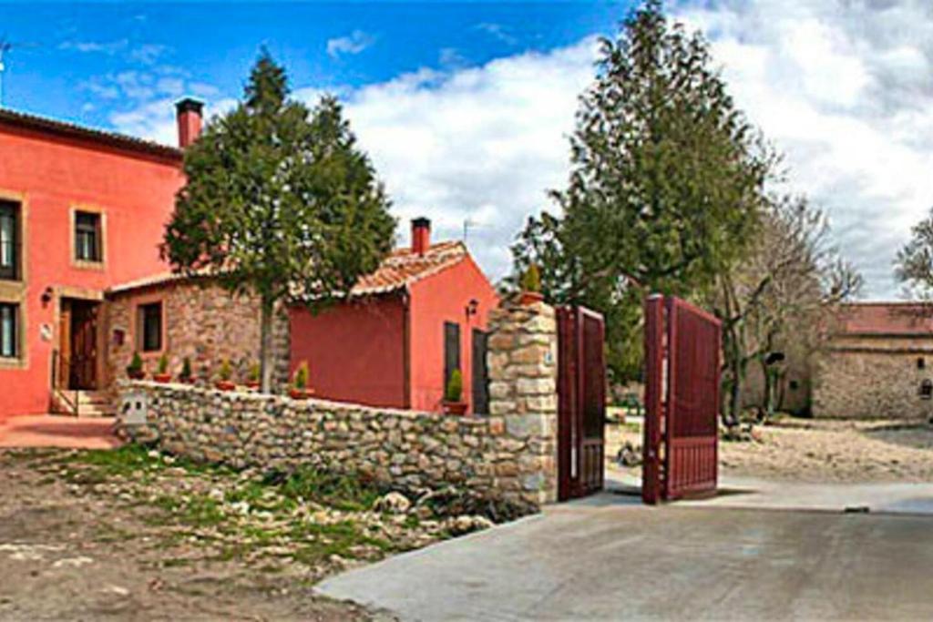 una casa roja con una puerta y una pared de piedra en 5 bedrooms house with terrace and wifi at Aldehuela Sepulveda, en Hinojosas del Cerro