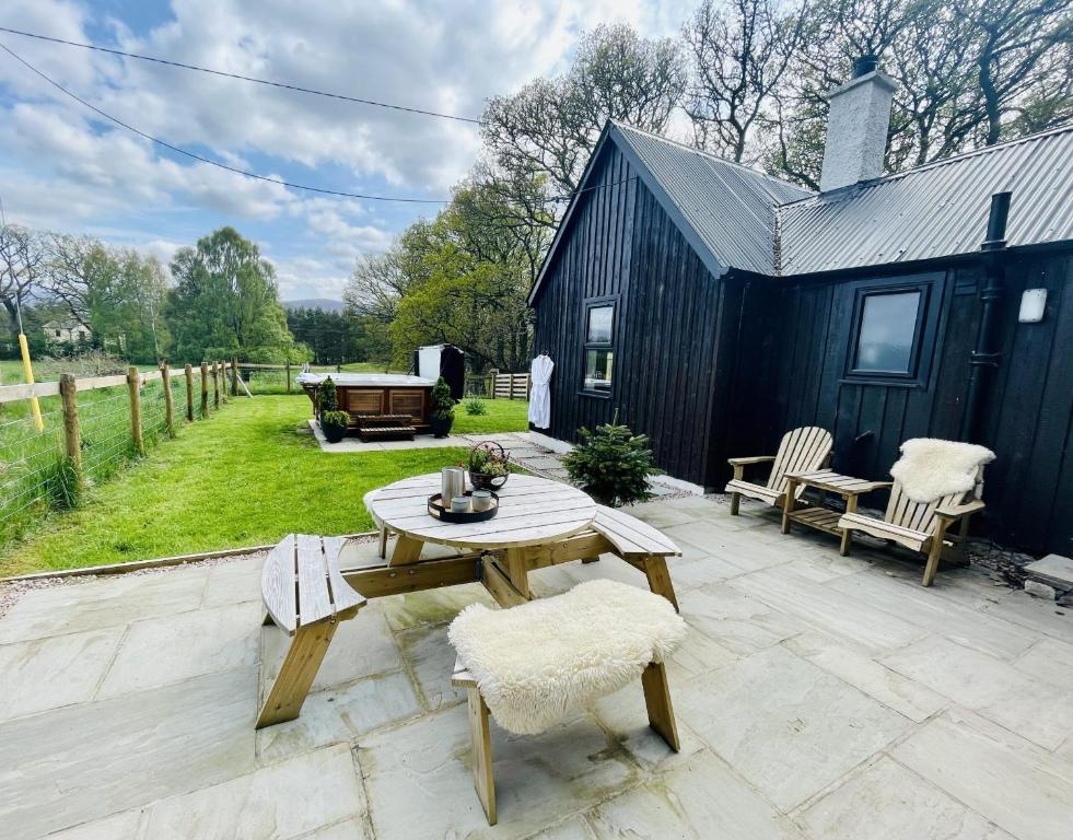 a patio with a table and chairs and a building at Eco lodge with hot tub overlooking Cairngorms in Aviemore 