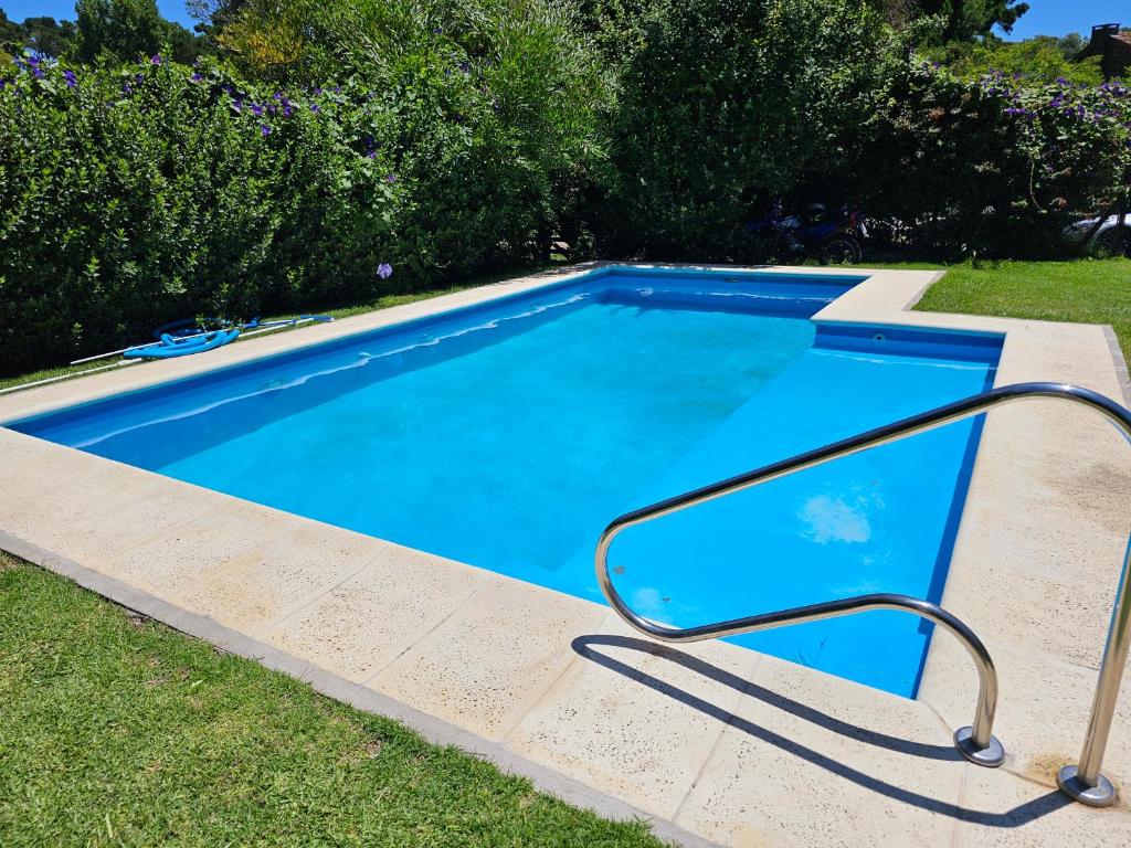 uma piscina azul com um corrimão na relva em Chalet Araceli em Pinamar