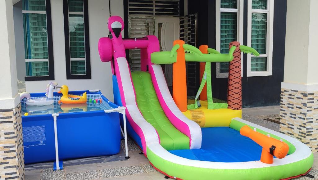 a inflatable water slide in front of a house at Villa Tamu Dr Din - Pool OR Soopa Doopa in Rantau Panjang