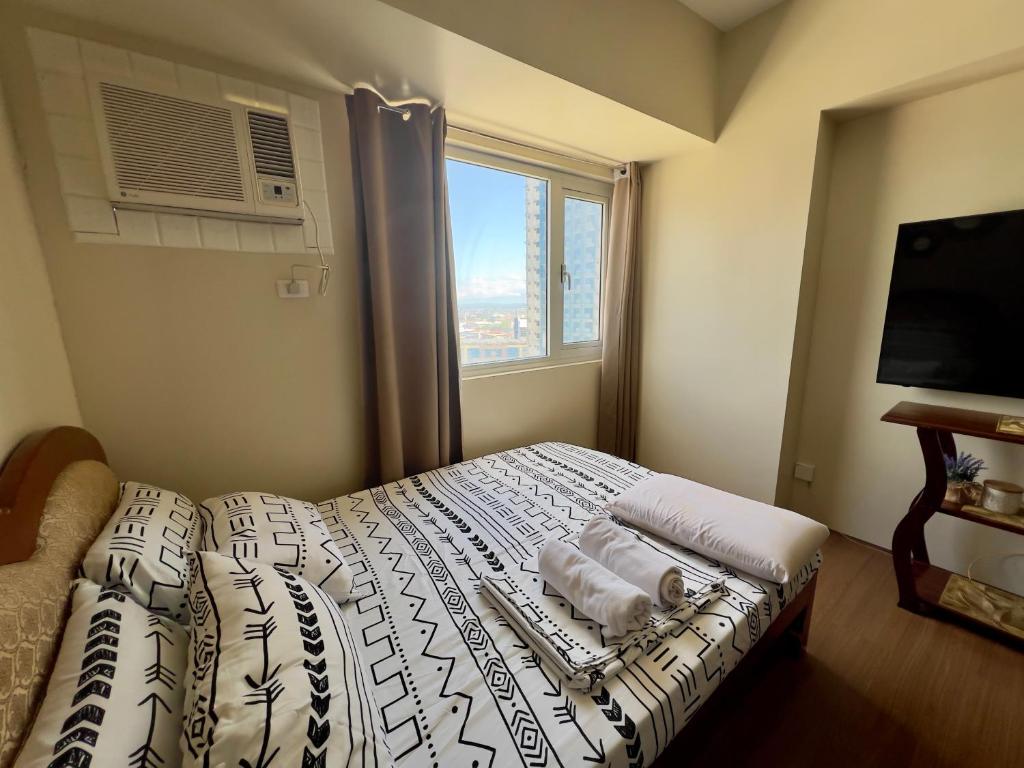 um quarto com uma cama com almofadas e uma janela em Condo near Ateneo and Royal Mandaya em Davao