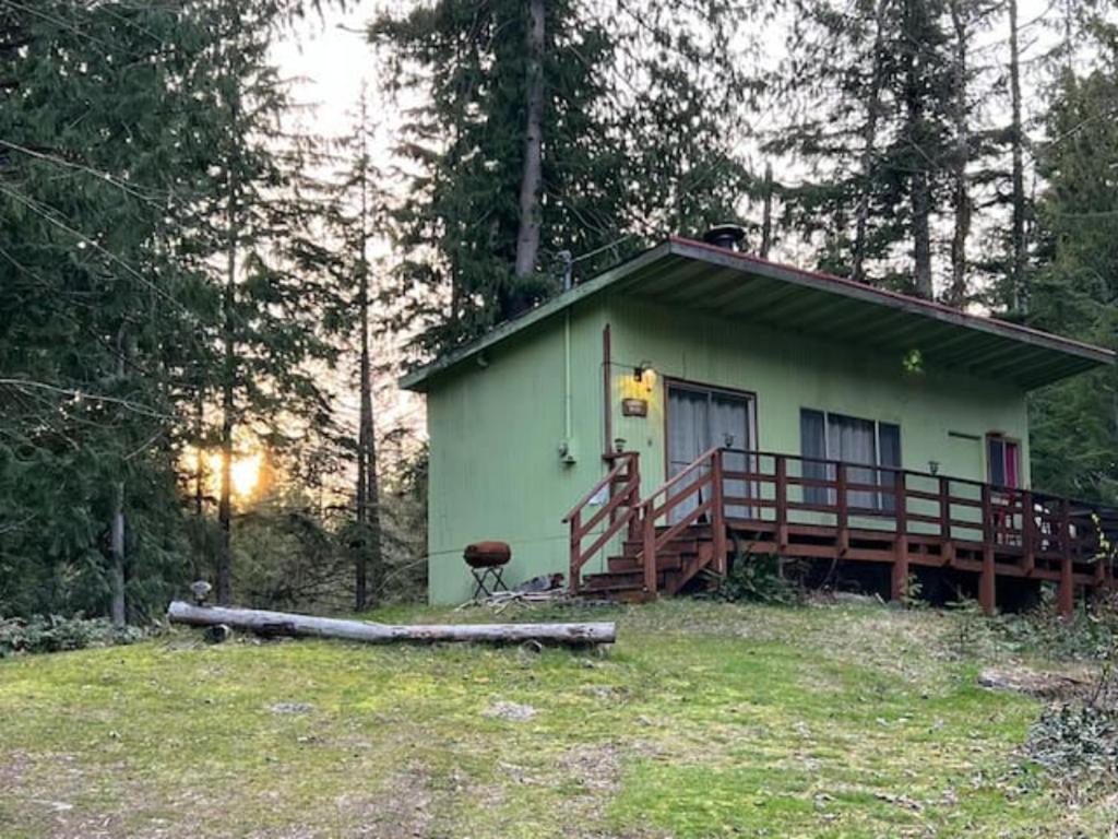 a small green house with a large deck in the woods at Green Hill at Rainier Lodge (0.4 miles from the entrance) in Ashford
