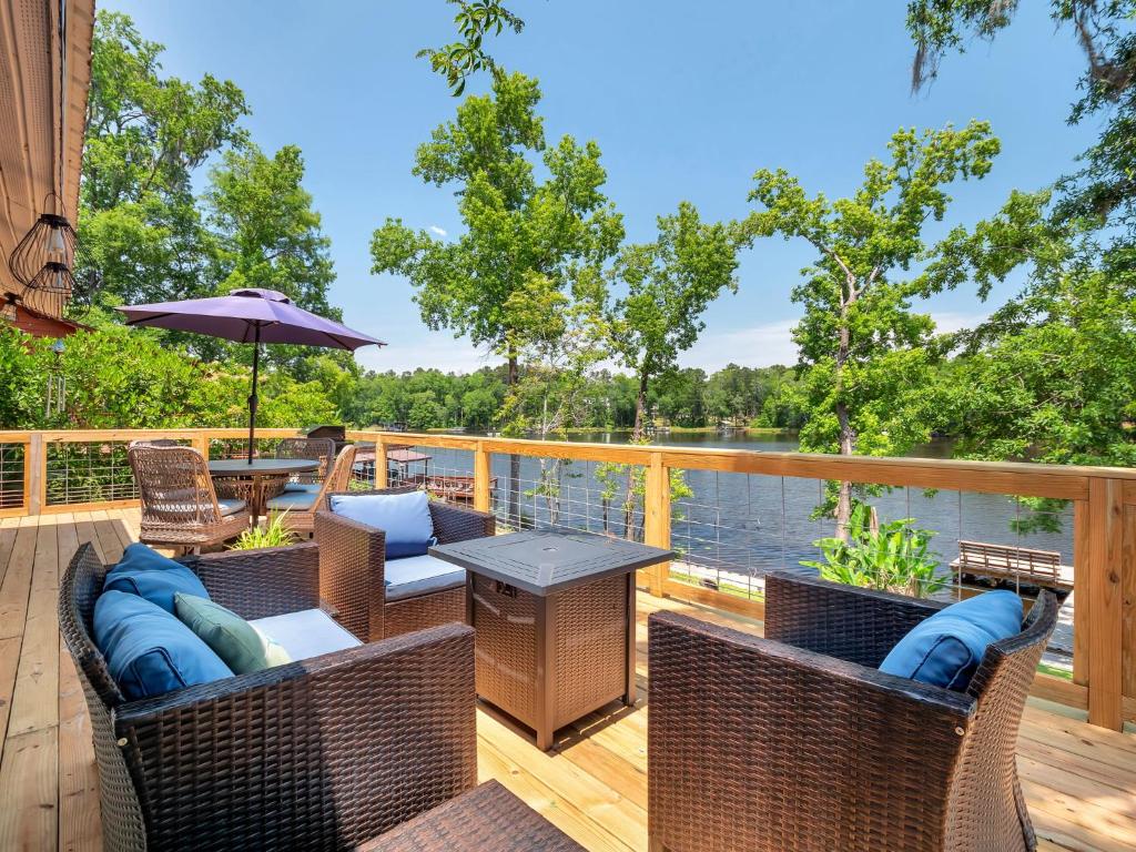 a deck with wicker chairs and a table with an umbrella at Waterfront on Lake Talquin - Near FSU - Stunning Views - 2 Story Deck - Fire Pit - Fast 1000 mbps Internet - 3 min from Boat Ramp in Tallahassee