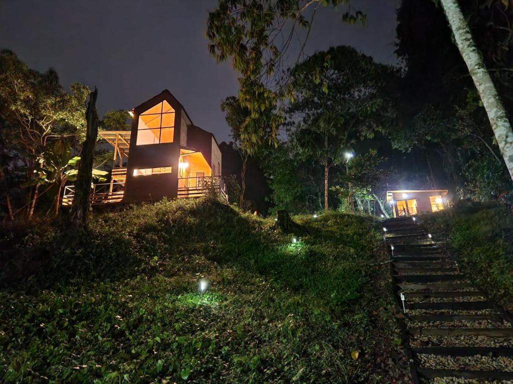 una casa con luces en el césped por la noche en Ecomariposa, en La Vega