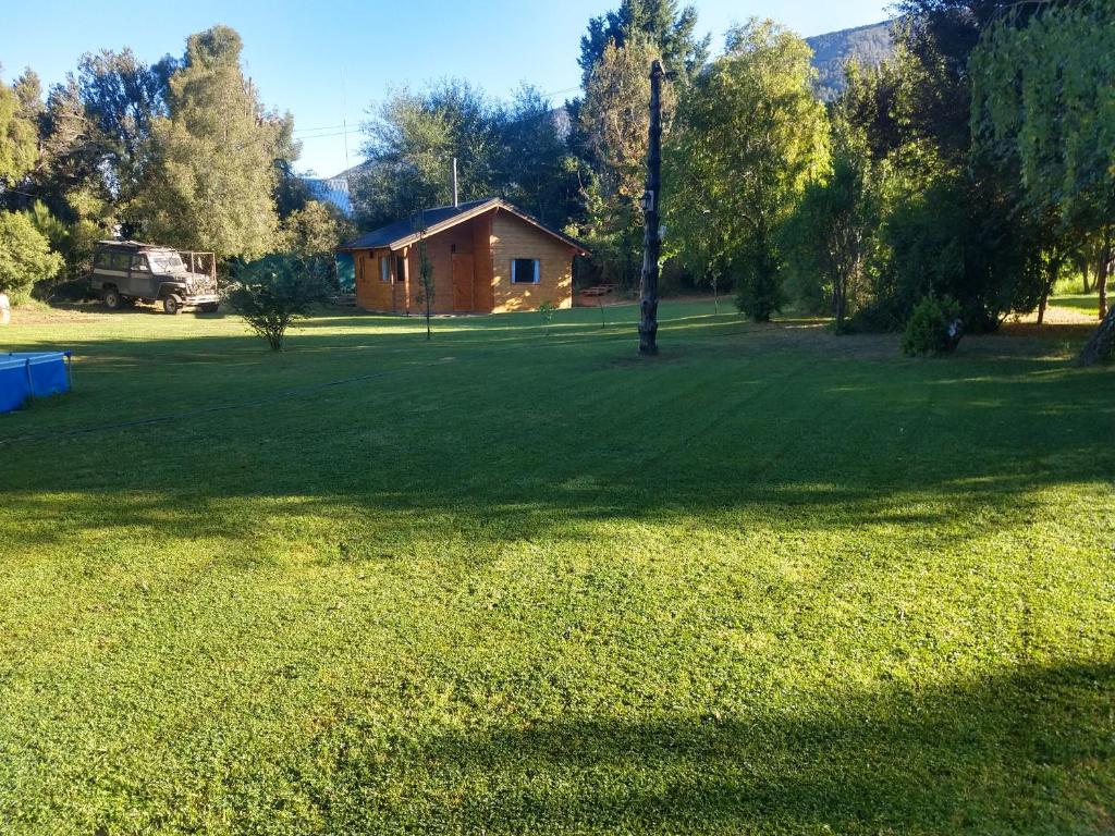 a large grass field with a house in the background at Vertientes de Lolog in Junín de los Andes