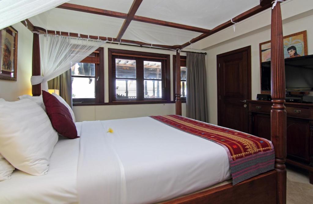 a bedroom with a white bed with a canopy at Villa Ocean in Tanah Lot