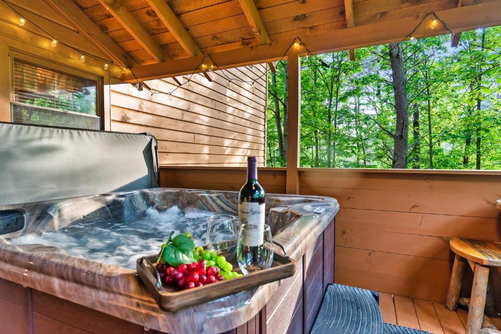 a hot tub with a bottle of wine and fruit at New! Cozy, ADA Accessible, Family Cabin w/ Hot Tub in Sevierville