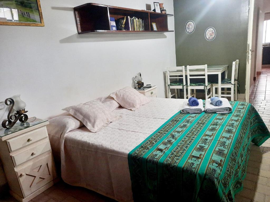 Un dormitorio con una cama y una mesa con toallas. en La Posadita Familiar en Yerba Buena