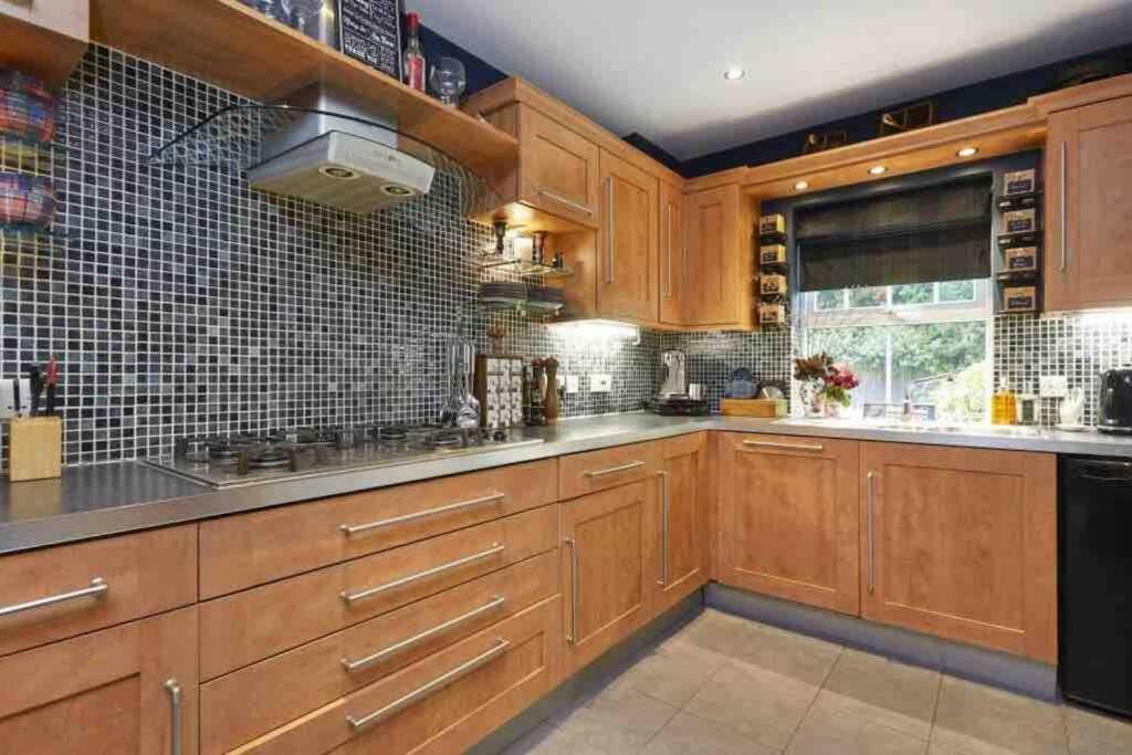 a large kitchen with wooden cabinets and black appliances at Stunning Racecourse Townhouse for Royal Ascot in Winkfield