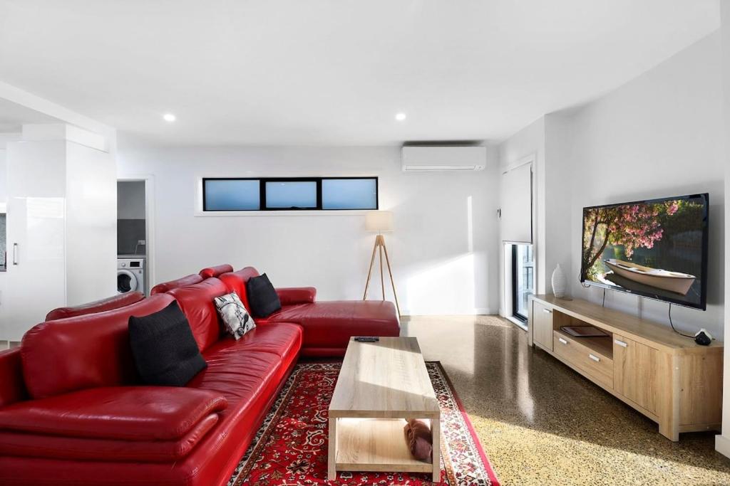 sala de estar con sofá rojo y TV en Raven West House I Corporate or Holiday en Geelong West