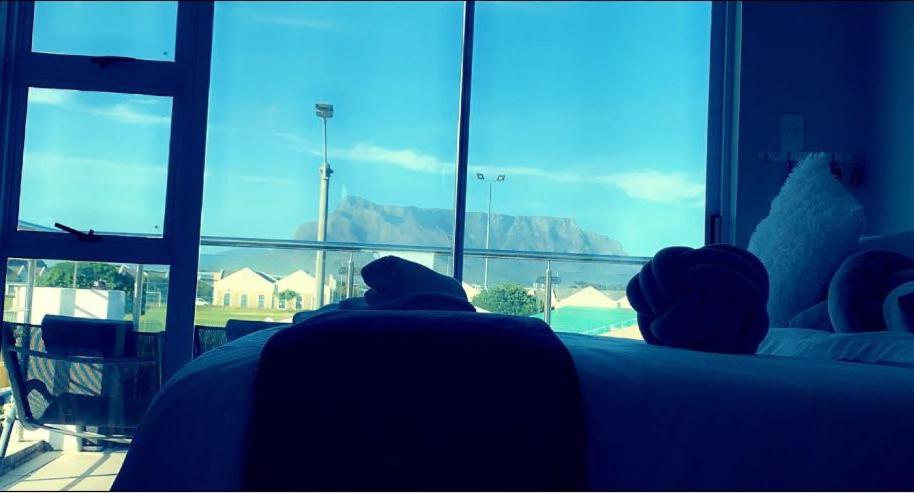 Un par de personas sentadas en una cama mirando por la ventana en Kwaaamiii, en Ciudad del Cabo