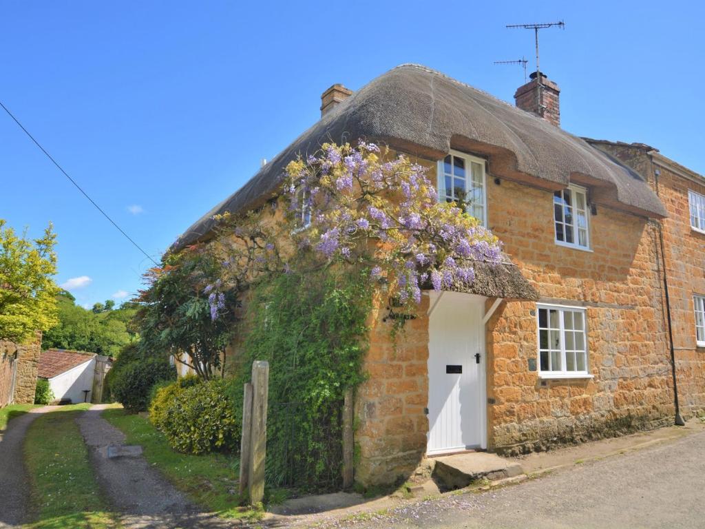 an old brick house with a thatched roof with flowers at 3 Bed in Beaminster 50738 in Stoke Abbott