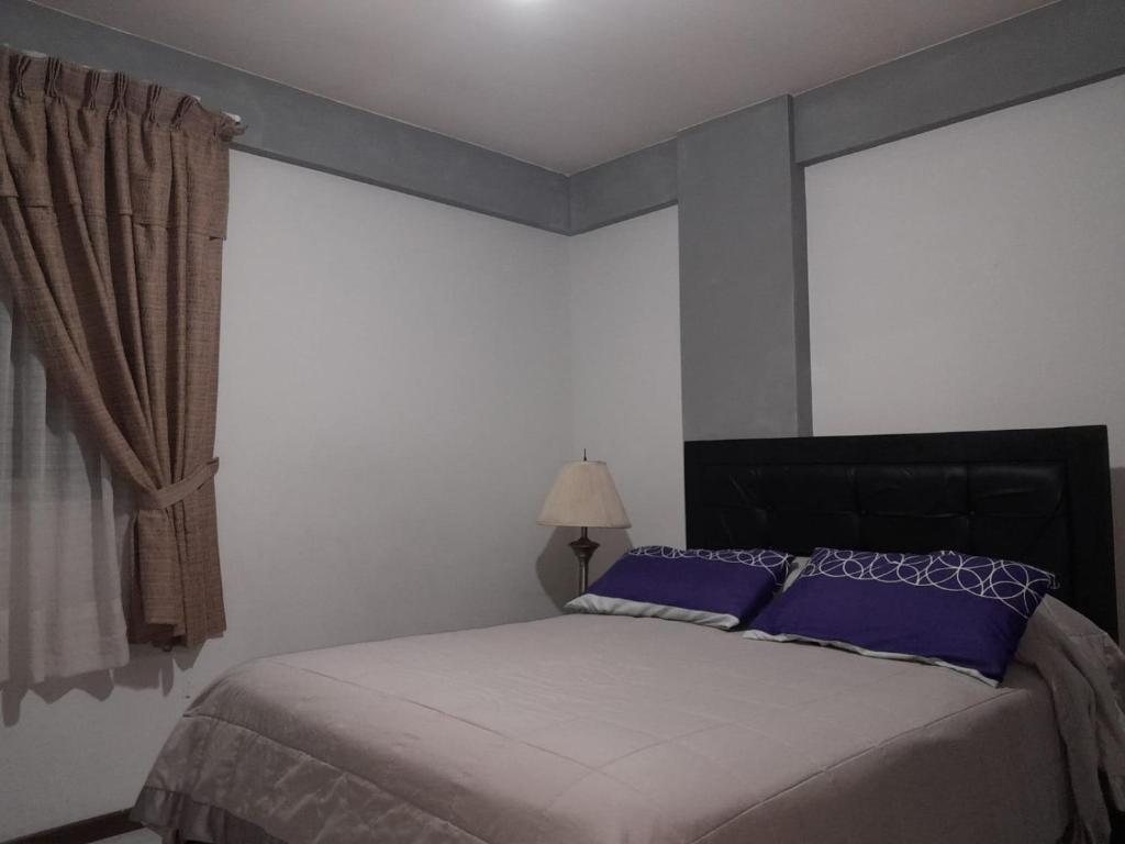una camera da letto con un letto con cuscini blu e una finestra di DEPARTAMENTO COMODO DUPLEX Zona Norte a Cochabamba