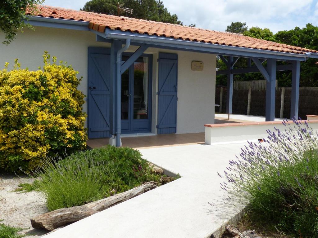 une maison avec des portes bleues et une terrasse dans l'établissement Maison T4 avec Grande Terrasse Couverte, Boulodrome et Jardin Clos - Biscarrosse - FR-1-521-218, à Biscarrosse