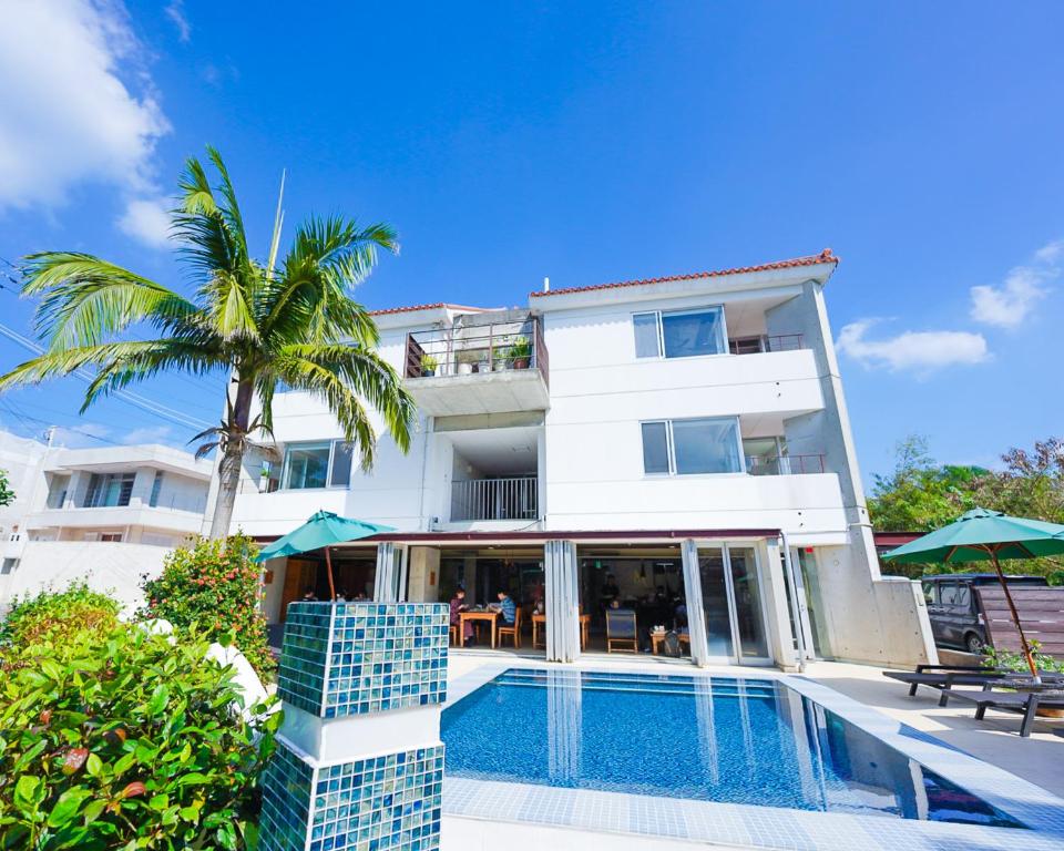 a white building with a swimming pool and a palm tree at Alaise De Bale Ishigaki in Ishigaki Island