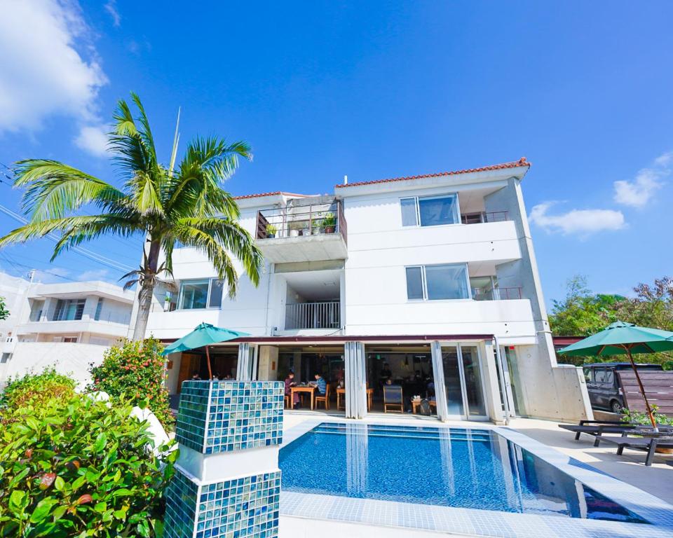 a white building with a swimming pool and a palm tree at Sky Ocean - Ishigaki Eco-Resort - Newly Renovated in Ishigaki Island