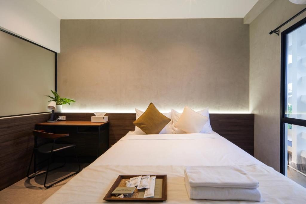 a bedroom with a bed with a table and a desk at C'HOUSE Bangkok in Pom Prap