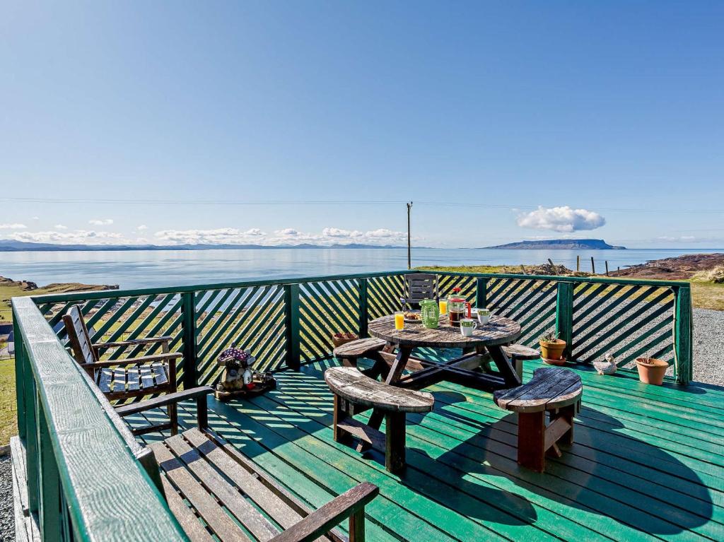 a deck with a table and chairs and the ocean at 3 Bed in Ardvasar CA071 in Aird of Sleat