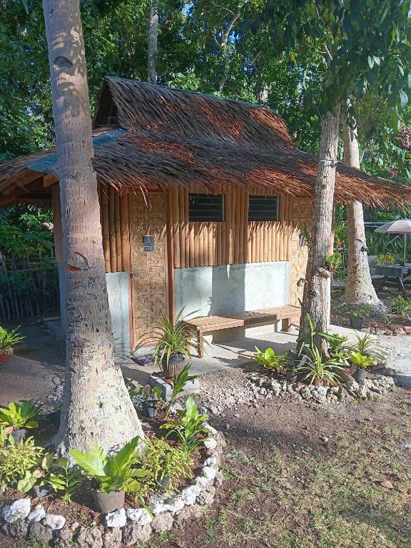 a wooden house with a bench in front of two trees at Elvira's Homestay in Looc