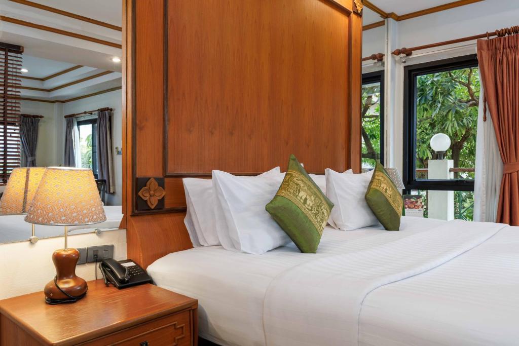 A close view highlights the bed, bedside lamp, telephone and garden-facing window.