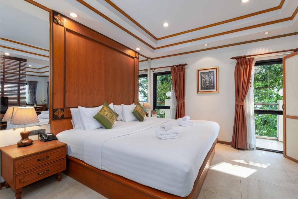 A bright double bedroom has a large wooden-framed bed and garden-facing windows.