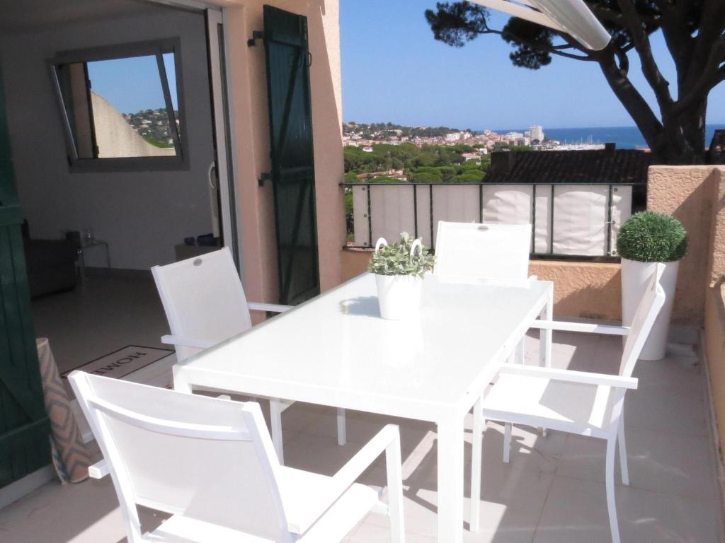 d'une table à manger et de chaises blanches sur un balcon. dans l'établissement Appartement 3 pièces, clim, piscine, parking à Sainte-Maxime - FR-1-780-24, à Sainte-Maxime