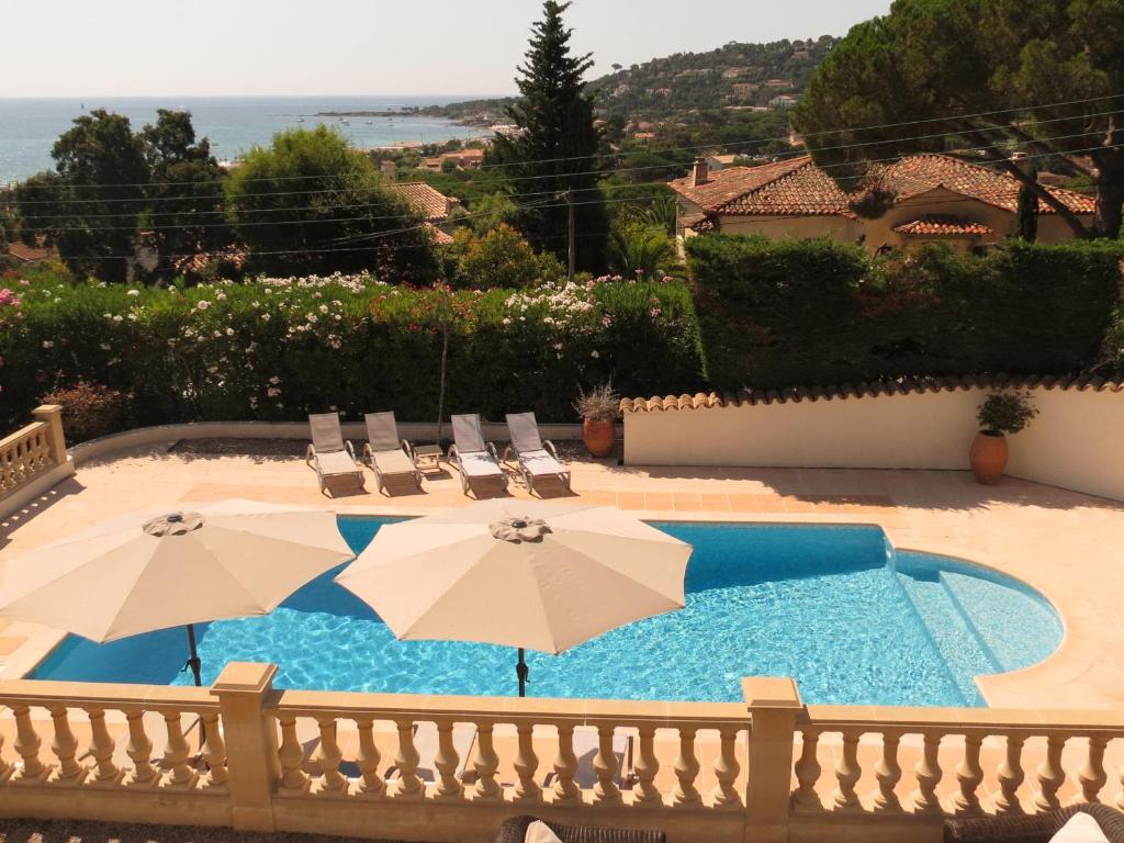 - une piscine avec deux parasols et des chaises dans l'établissement Villa 5 pièces + appart, piscine privée, clim, proche plages - FR-1-780-16, à Sainte-Maxime
