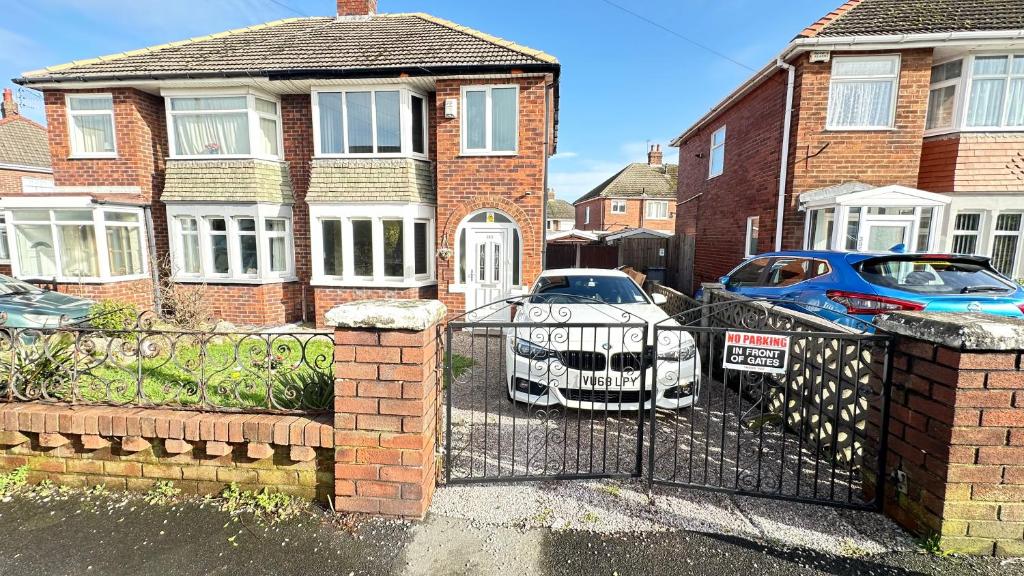 a house with two cars parked in front of a gate at Nyza's cosy House in Blackpool