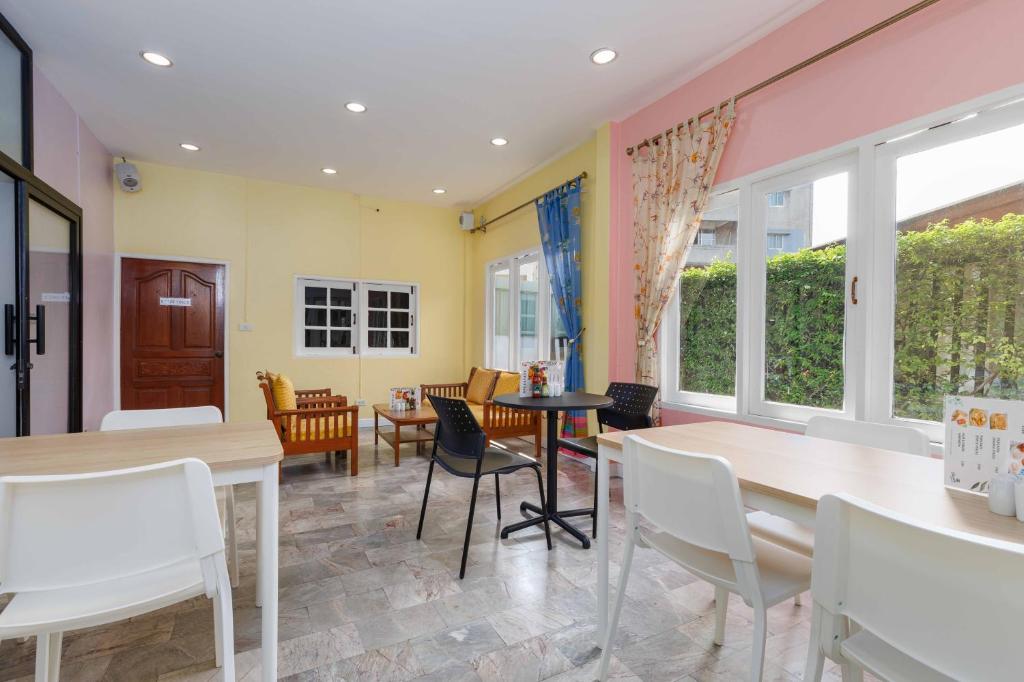 A pastel dining room with garden-facing tables and mixed seating.