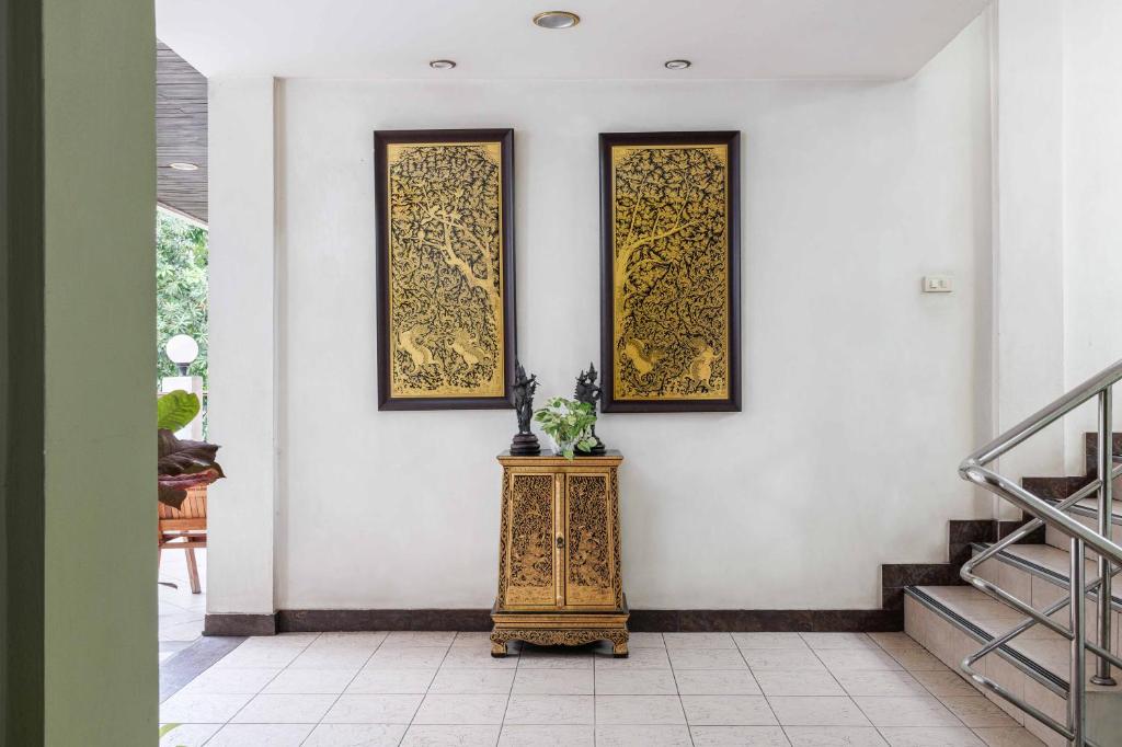 An ornate entrance hall with Thai-style artwork, a cabinet, and a staircase.