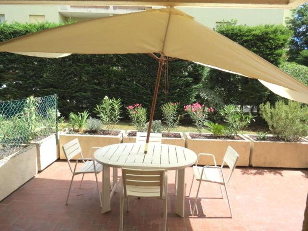 - une table et des chaises avec un parasol sur la terrasse dans l'établissement Appartement Sainte-Maxime, 1 pièce, 4 personnes - FR-1-780-61, à Sainte-Maxime