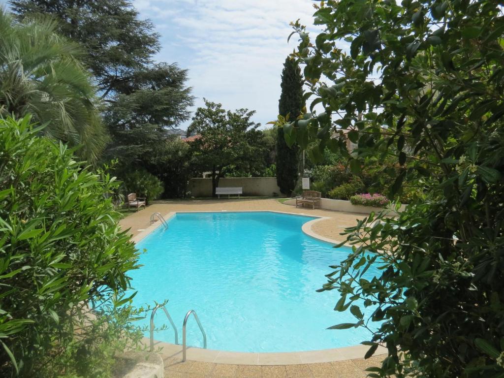 une grande piscine bleue entourée d'arbres dans l'établissement Appartement 2 pièces climatisé avec garage, piscine, proche commerces et plages - Sainte-Maxime - FR-1-780-66, à Sainte-Maxime
