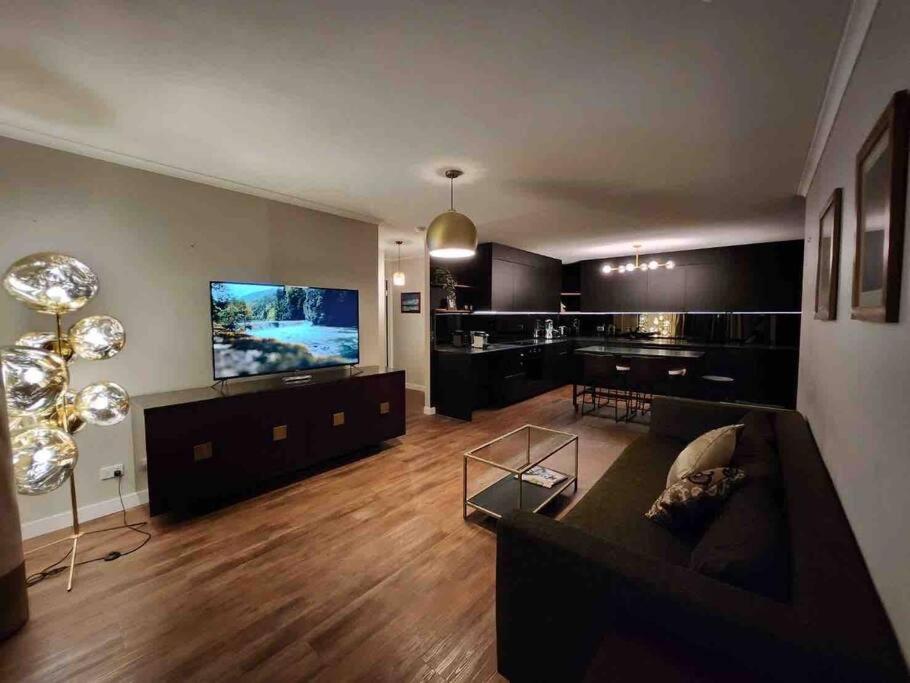 a living room with a couch and a flat screen tv at South Brisbane modern apartment in Brisbane