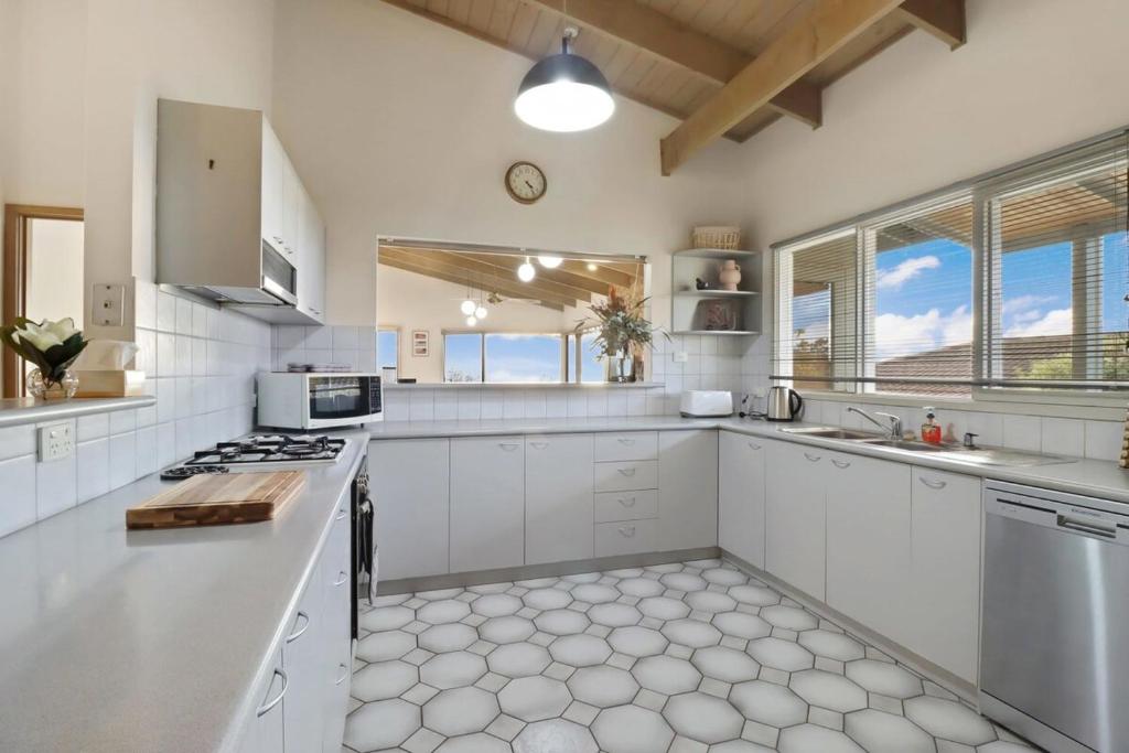 a large white kitchen with white cabinets and windows at Seven Views I Pool Table n Water Views in Clifton Springs