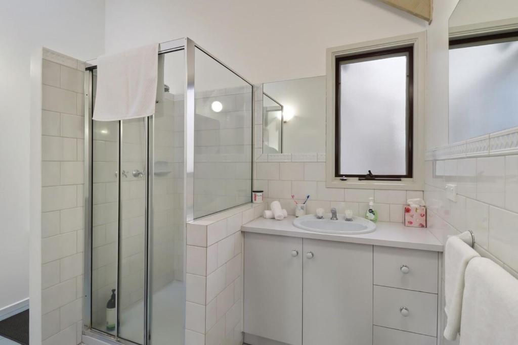 a white bathroom with a sink and a shower at Seven Views I Pool Table n Water Views in Clifton Springs