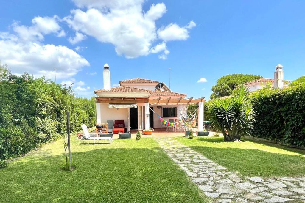 a house with a lawn in front of it at 3 bedrooms chalet with shared pool terrace and wifi at Conil de la Frontera 7 km away from the beach in Hozanejos