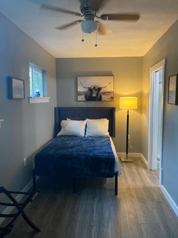 a bedroom with a blue bed with a ceiling fan at ATX Tiny House in Austin