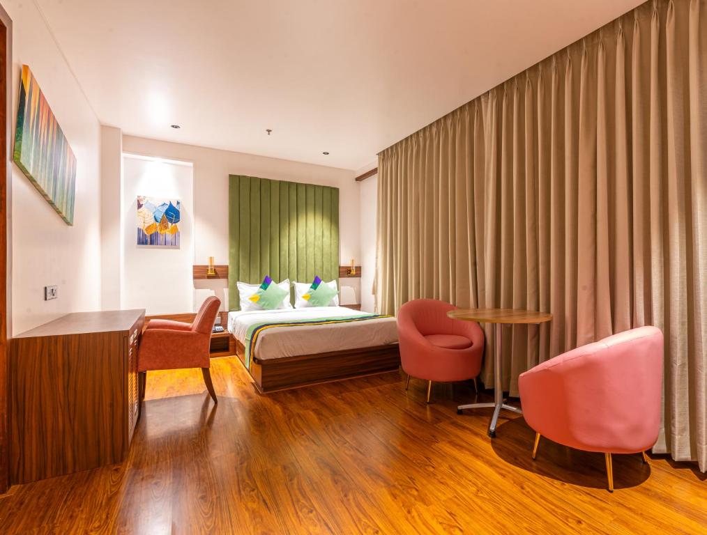 ムンバイにあるTreebo Tryst Heritage Grand - Thaneのベッド、デスク、椅子が備わるホテルルームです。