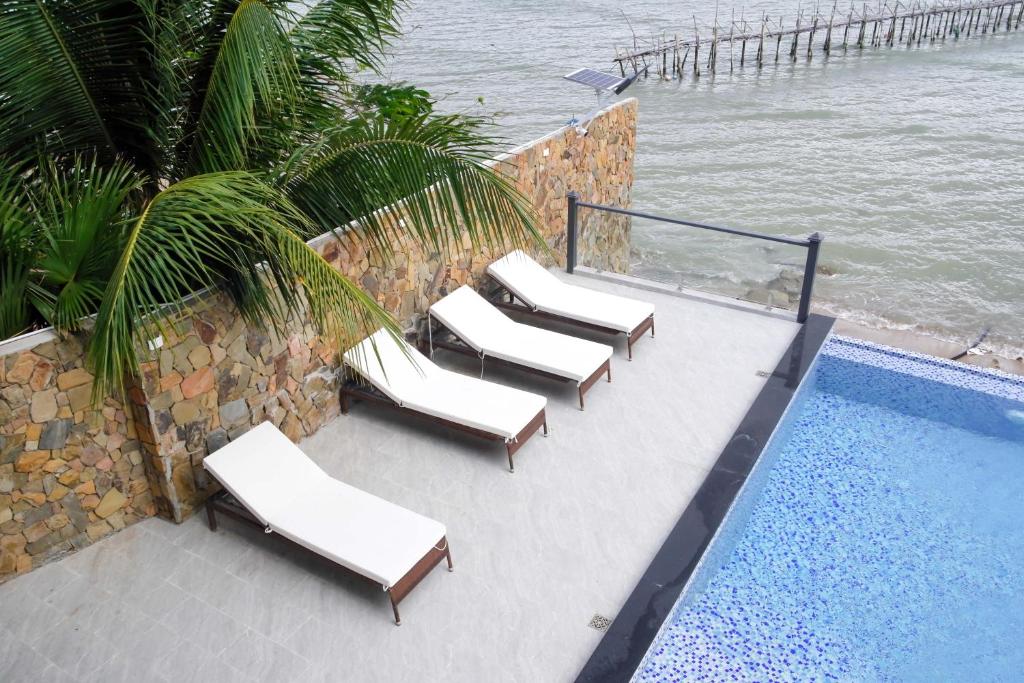 a group of lounge chairs next to a swimming pool at Eroska Villa in Thôn Cát Lợi