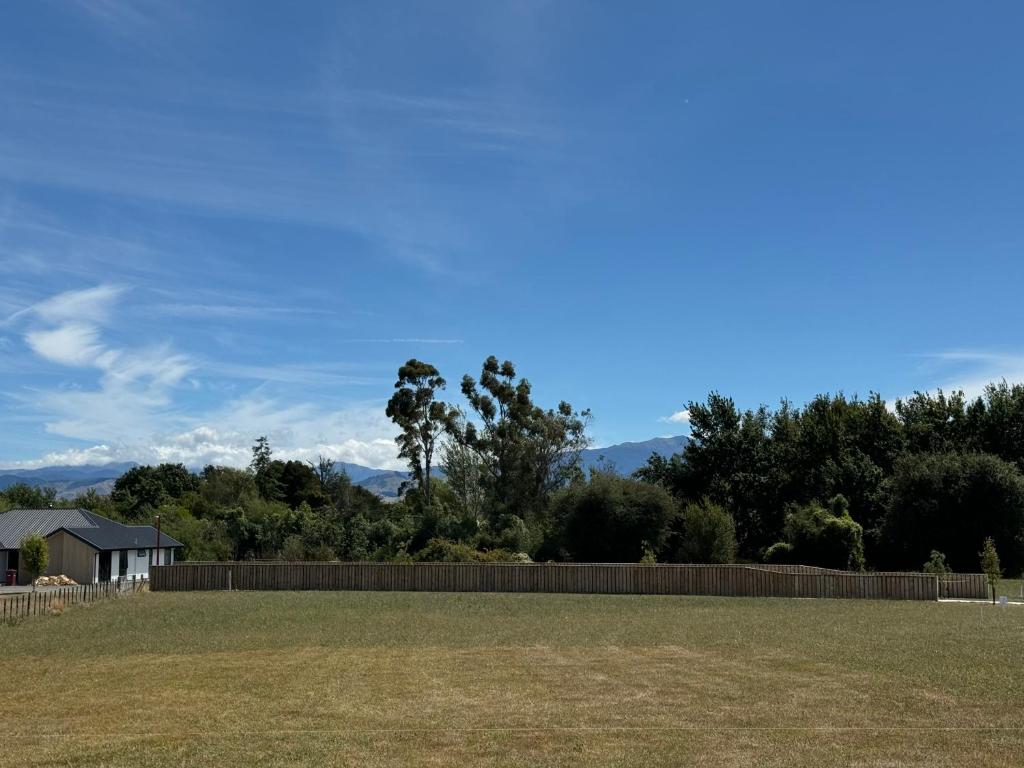 a field with a fence and trees in the background at Cashmere B&B in Masterton