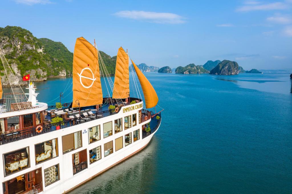 un crucero en el agua con montañas al fondo en Emperor Cruises Legacy Ha Long, en Ha Long