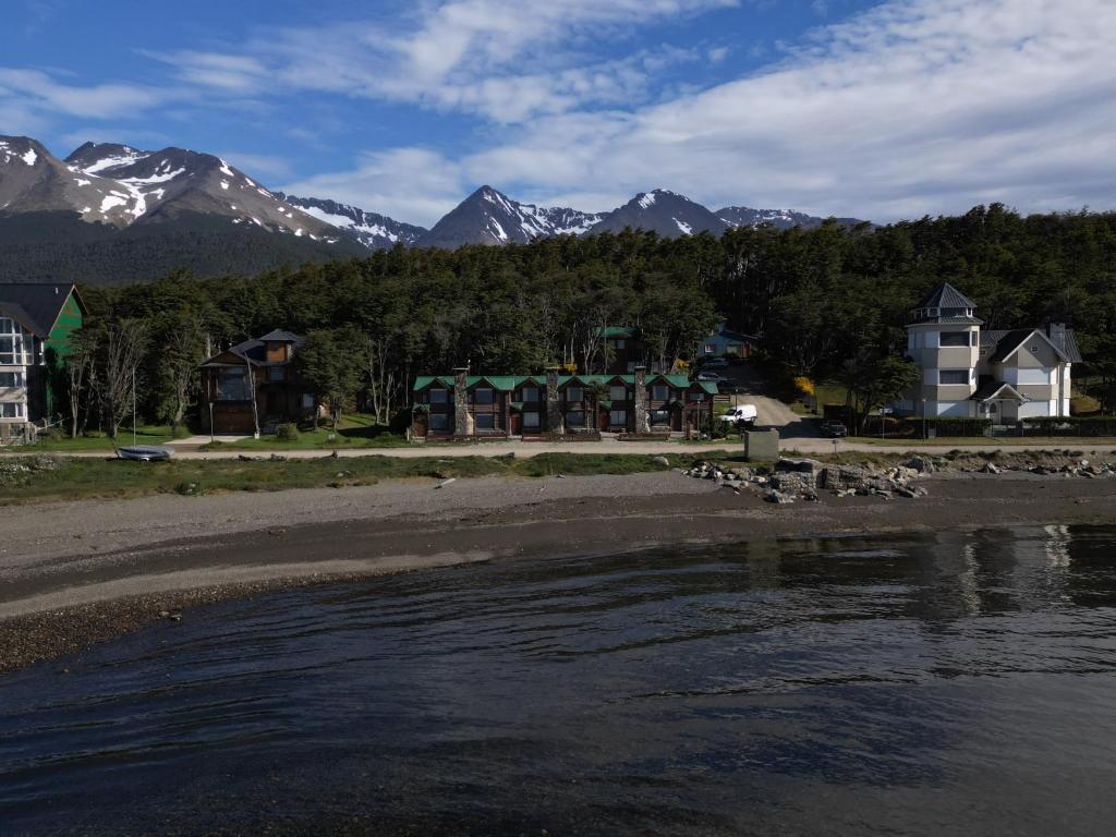 a group of houses on a beach with mountains in the background at COSTA DE LOS PAJAROS in Ushuaia